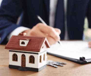 Model size house with someone signing property contract